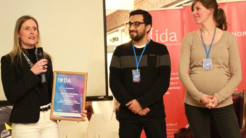 Premio entregado por Katherine Exxs y Nicolás Espinoza de IxDA Viña del Mar, recibiendo la directora del MHNV, Loredana Rosso